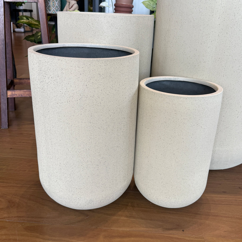 Set of three beige planters with black interior on a wooden floor