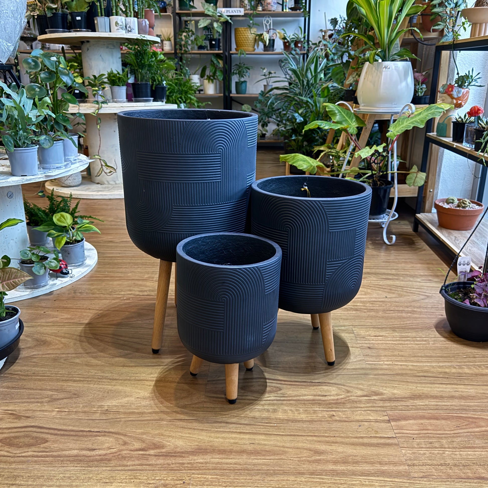 Set of three modern tripod planters in small, medium and large sizes styled with indoor plants