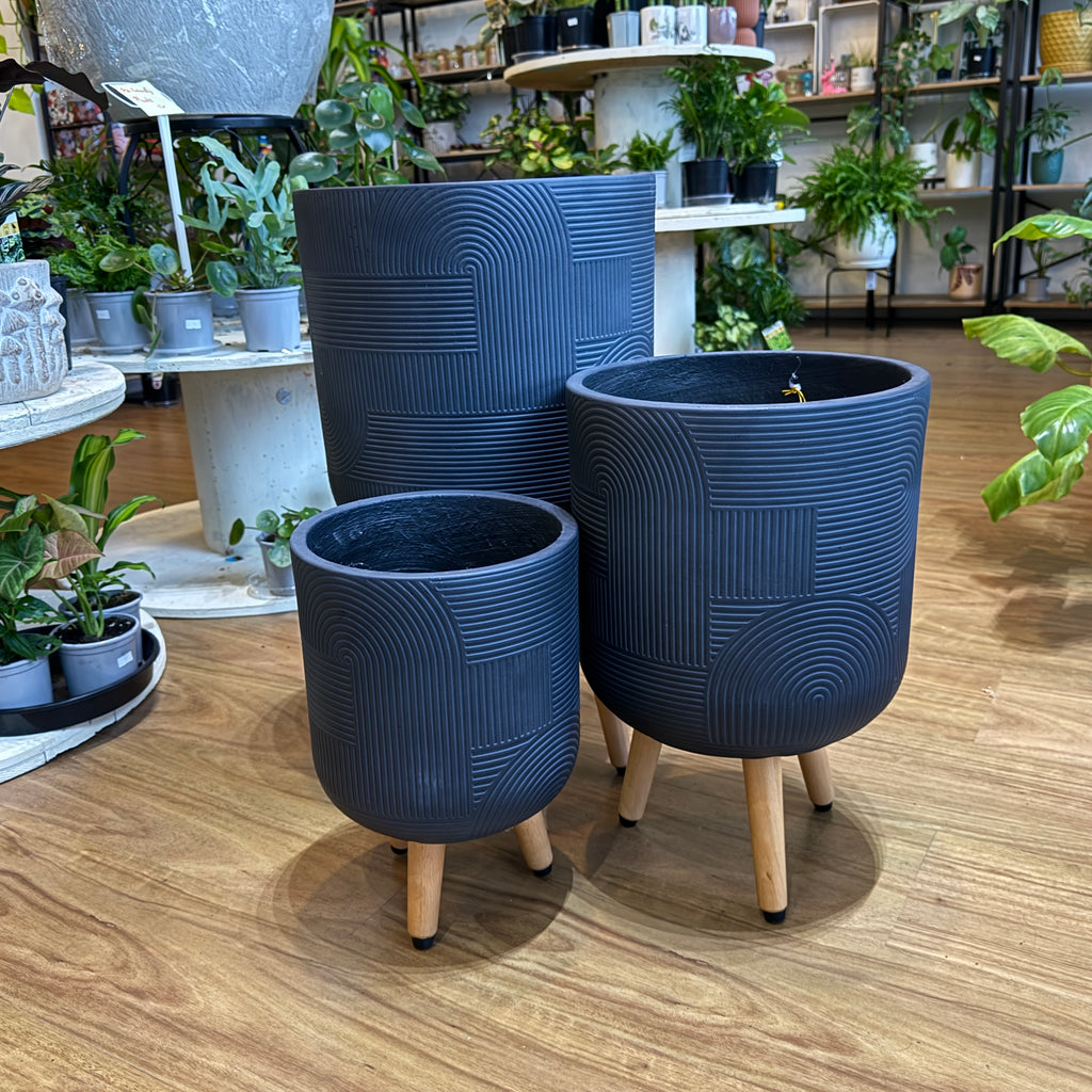 Set of blue textured planters with wooden legs on a wooden floor.